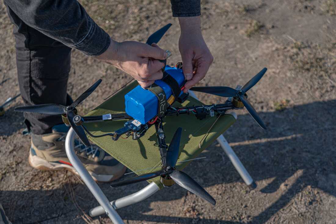 Team member of Vyriy production copmany preparing fpv drone for flight at a testing field in Kyiv.