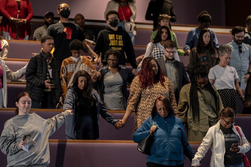 People hold hands along the pews of a church.