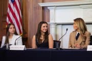 Three women look at each other while seated at a table.