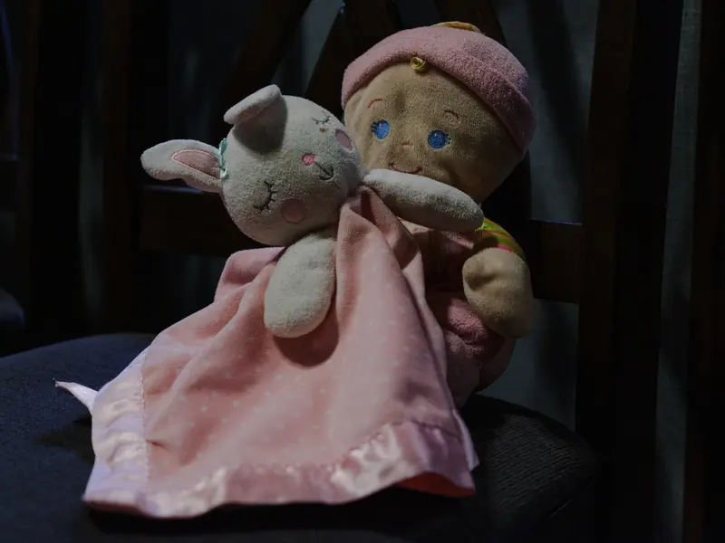 A stuffed rabbit and doll wearing a pink hat.